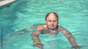 Grandma swims in the pool. Old active woman goes in for sports and swims in the pool