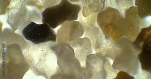Sand under a microscope. Small rocks under a scope. Crystals under magnification zoom. Glass under a microscope. Microscopic world of beach sample. Studying the consistency of sand with a microscope