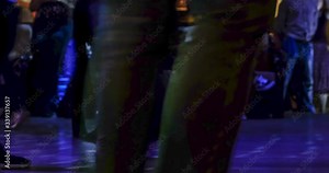 Time lapse on the movements of dancers, their legs and shoes, during disco dancing, social dancing, in a dark interior with illumination.
