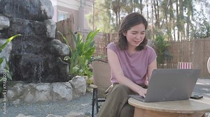 Young happy smiling Asain woman in cafe working video call facetime type project working on her laptop notebook personal computer, Female begins typing say hello on laptop