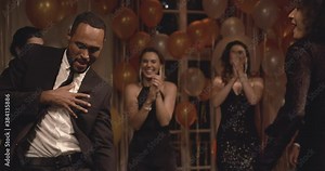 Handsome young man dancing surrounded by his friends at gala night. Group of people dancing at party.