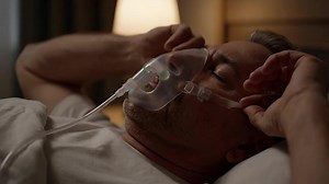 Download Man Sleeps in Bed Wearing Oxygen Mask, Late at Night in Bedroom at Home for free