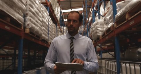 clip-3996260613-warehouse-manager-walking-aisle-tapping-tablet-projecting