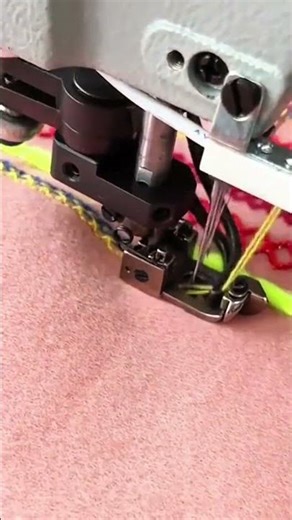 stitching a colorful pattern onto a pink cloth using an industrial sewing machine with neon thread