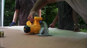 Building contractor worker using hand held worm drive circular saw to cut boards on a new home constructiion project