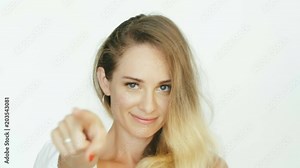 Smiling woman pointing with index finger at viewer looking on screen