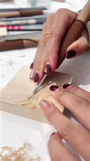 carving delicate leaf patterns into a wooden surface using a fine gouge for detailed art today