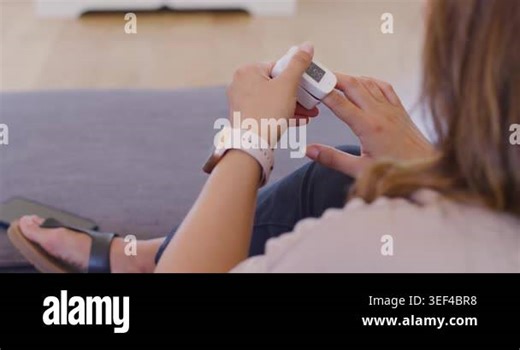 African American lady on sofa holding oximeter slipping on finger checking O2 by cell, copy space. Health, monitoring, wellness, smartwatch, wearable, phone, gadget Stock Video Footage - Alamy