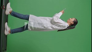Full Body Of Side View Asian Female Doctor With Stethoscope Using Smartphone While Walking On Green Screen Background In The Hospital