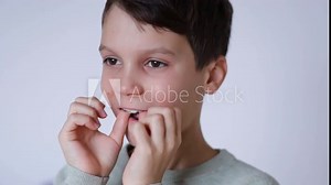 A boy puts on retainers, on a white background. Concept of correcting crooked teeth and occlusion in a child, installing a jaw expander.