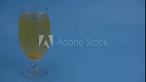 Vitamin C effervescent drug dissolving in glass of water on blue background with copy space for text.