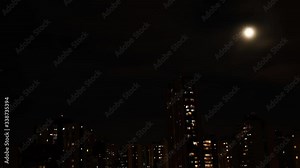 Day to night city timelapse where the moon rises and buildings flats lights go on and off