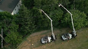 Wide footage. Safety tree trimming by work crew from company to keep tree limbs from encroaching on the electrical power lines. aerial shot Stock Video