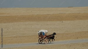The Great Pyramid in Giza and tourists on a horse carriage riding on the wat to the pyramids in Cairo, Egypt
