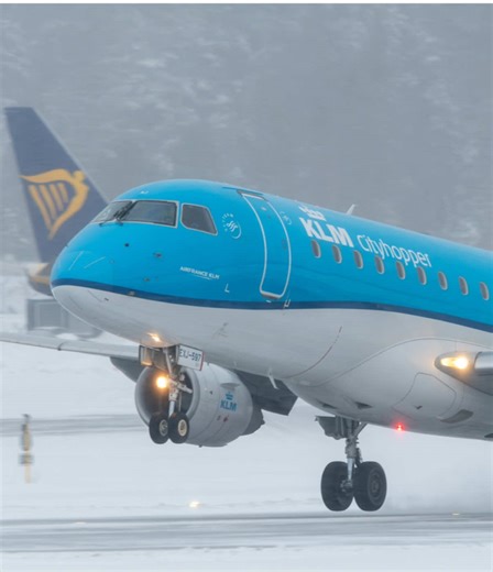 A KLM Embraer 175 begins its takeoff on a snowy day, engines pushing the regional jet into cold, dense air as snowflakes drift across the runway. The clean blue livery contrasts beautifully with the winter backdrop, creating a calm yet atmospheric departure moment. #aviation #avgeek #plane #aircraft #planespotting