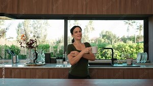 Happy old grandmother confidently standing pose while look at camera for good event or anniversary in kitchen. Cheerful senior enjoy retirement life with beautiful kitchenware and house. Divergence.