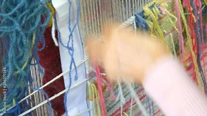 Handmade carpet embroidery. Women's hands create a pattern using multi-colored threads. Hammer for embroidery quors, stuffing threads. Close up view.