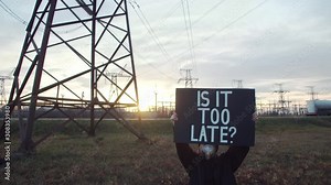 Young beautiful woman holding poster IS IT TOO LATE? Global warming. Worldwide politics problems. Climate change. Society future. Ecology protection concept. Old Private Factory on background.