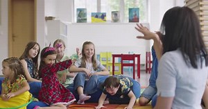 Storytime Elementary or Primary School Teacher Reading a Story to a Group of Children in a Daycare