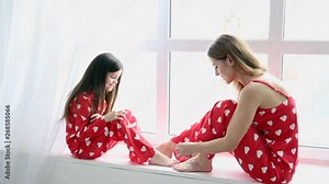 mother and daughter painting each other nails and toe nails in the bedroom