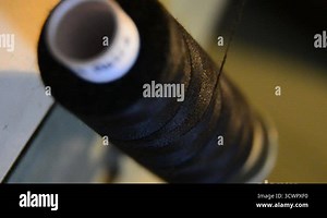 spool of black thread with needle stuck. Unrolls during process of sewing on machine in clothing industry production, Extreme close up, selective focus Stock Video Footage - Alamy