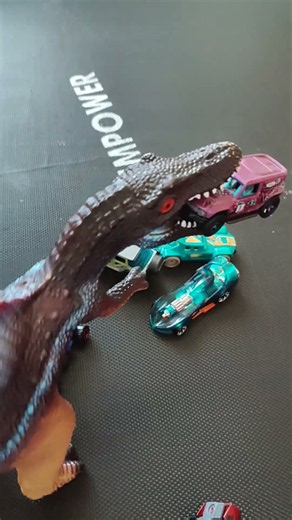 The dinosaur is eating the cars.