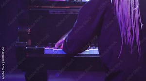 Closeup of female pianist's hand playing black piano professionally in dark room. Rear view. Woman in black clothes and white hair playing piano concerto