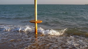 Waves breaking around an umbrella - Free Stock Video