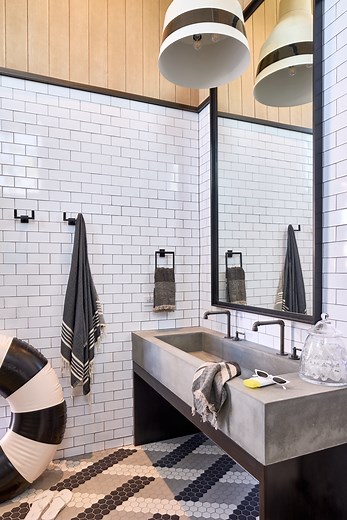This pool bathroom at #ProjectBlowingYourMind was designed with equal parts style and function. From the oversized concrete trough sink to the crisp subway tile and patterned hex flooring, every detail elevates a space that usually gets overlooked. And because this home is all about family and fun, we built it to handle the traffic that comes with long pool days. The bathroom also includes a urinal and a kinder-sized toilet to make it effortless for guests of all ages. Thoughtful design, durable