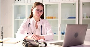 Doctor communicates remotely from laptop with patients or doctors via Internet via video call