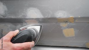 Car body shop. Repair man processes the welding seam using an angle grinder on replaced car part. Professional Body master grind old paint and rust. Rusty damage. Rusting car. Hands with tool close-up