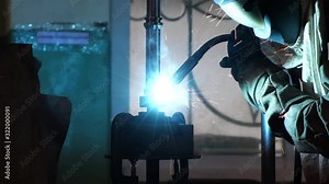 blacksmith welder in protective mask works with metal steel and iron using a welding machine.