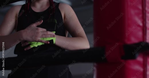 Watch a dedicated female boxer meticulously wrap her hands, preparing for a tough training workout where safety, strength, and technique are paramount.
