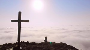 Aerial zoom out view of young confident female person standing on hill and enjoying scenic panorama above clouds