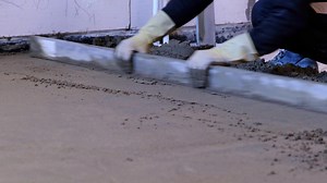 Download Leveling with a construction spatula of semi-dry floor screed. Construction of a concrete floor in the house, a master with special equipment. Slow motion for free