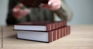 Librarian throws thick books with brown hardcovers on wooden table. Woman gives out professional material for students in library slow motion