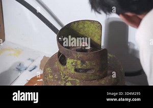 A man installing a green LPG gas regulator at home. The process shows how to properly connect the regulator to the small household gas cylinder safely and carefully. Suitable for footage about home.