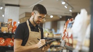 clip-3500044015-man-black-t-shirt-apron-walks-along-supermarket