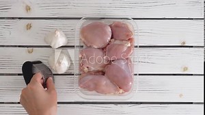 Chef marinating chicken thighs with soy sauce, turmeric, black pepper, seasoning, and fresh garlic. The cooking process, ingredients close-up