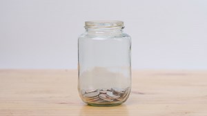 Download Stop motion animation coin into a clear glass jar on wooden desk. Savings and Investments concept. for free