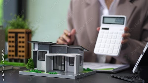 Home loan officer uses a calculator to calculate with a house plan.