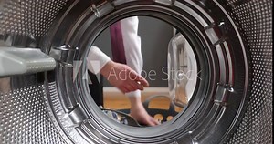 View Looking from the inside Washing machine As the businessman's hands load, take the laundry out of the washing machine. Man in a white shirt is doing laundry.
