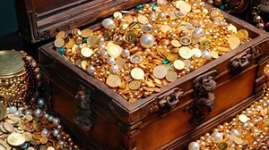 A wooden chest filled with lots of gold and pearls