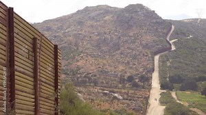 A Border Patrol vehicle moves along the U.S. Mexico border wall fence in the California desert.