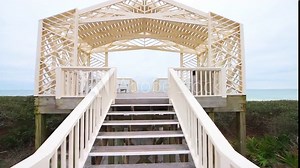 Point of view pov handheld walking up stairs steps of wooden pavilion gazebo by beach sea ocean of Gulf of Mexico at Seaside, Florida with new urbanism white wooden architecture