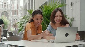 Asian girls and African American students Discussing at College campus on laptop - Concept of young people using technology for learning - young woman explaining to her colleague by looking on the