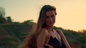 beautiful tall girl stands on beach sunrise savoring calm of morning Her long hair flows gentle ocean breeze as she gazes horizon