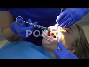 female dentists in purple latex gloves inject female patient with cheek retractor