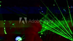 Silhouettes of a male go go dancer dancing in a nightclub with a laser light show