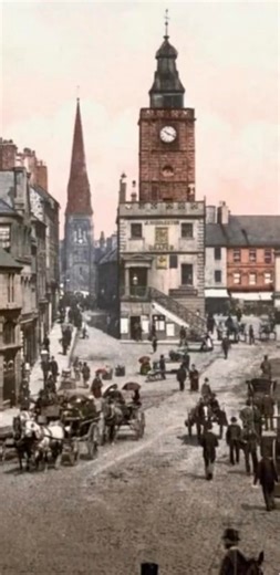 A colorised photo of Dumfries High street on a rainy day from 1895 brought to life at 3.50 pm going by the Mid Steeple clock probably around springtime of that year . This was a very difficult process using AI animation to minimise auto generation and keep the originality of this snapshot moment in time of 1895 Dumfries. | Dumfries Memories
